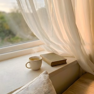Serene window seat corner wall art with sheer curtains and soft light, open book and coffee on beige ledge, Japandi slow living print, cozy reading nook interior, neutral minimalist home decor, digital printable photography