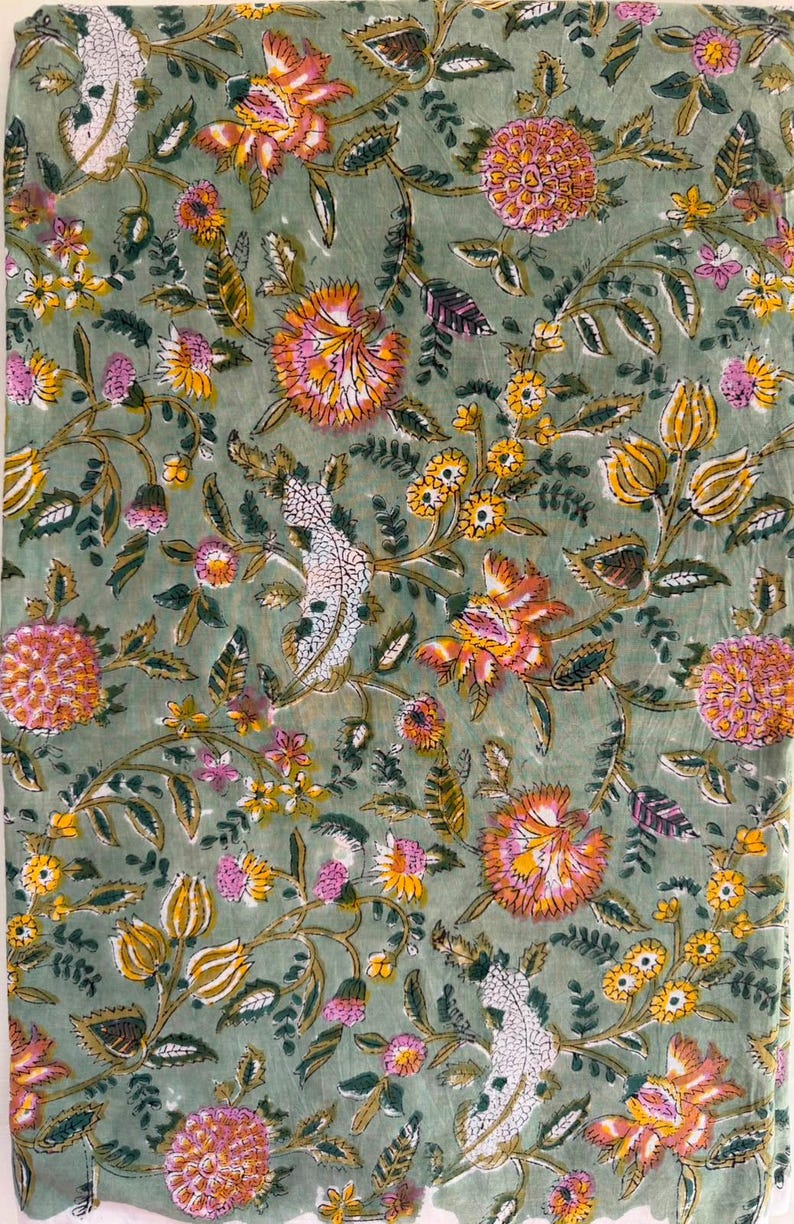 May include: A sage green fabric featuring a repeating floral pattern with pink, orange, and yellow blossoms, along with dark green leaves and white textured botanical elements, creating a dense, colorful, and intricate nature-inspired design.