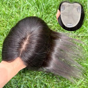 May include: A dark brown hair topper with a natural-looking part. The hairpiece has a mesh base with clips for secure attachment. The hair is straight and appears to be human hair, designed to add volume and coverage.