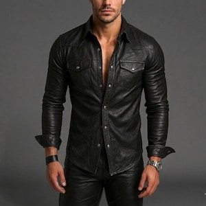 Peut inclure: Chemise en cuir noir avec deux poches poitrine et fermeture boutonnée. La chemise a des manches longues avec des poignets boutonnés. Le modèle porte une montre en cuir noir et un bracelet en cuir noir. La chemise fait partie d'une tenue en cuir.