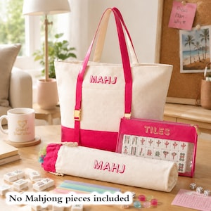 Peut inclure: Un sac fourre-tout en toile couleur crème avec des sangles rose vif et le mot MAHJ brodé en rose. Il comprend une pochette à cordon assortie avec MAHJ brodé en rose et une pochette zippée rose avec l'inscription TILES.