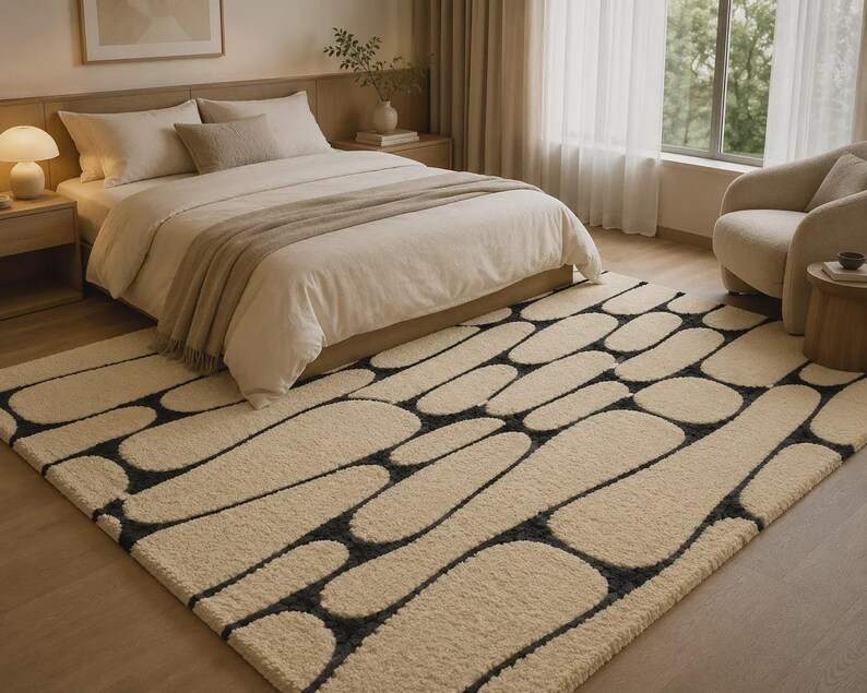 Puede incluir: Una alfombra rectangular de pelo largo en color crema con un patr&oacute;n repetitivo de formas redondeadas similares a guijarros, delineadas con l&iacute;neas de color gris carb&oacute;n oscuro. La alfombra cubre una gran parte del suelo con su textura.