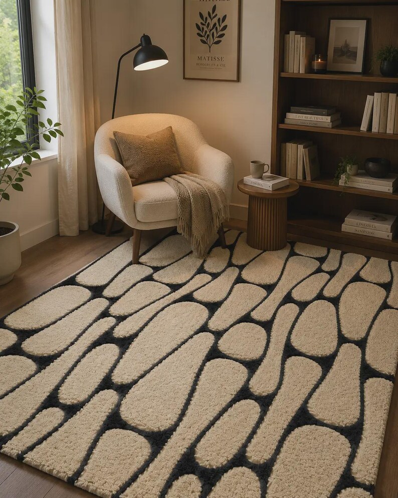Puede incluir: Una alfombra rectangular con un patr&oacute;n de guijarros de pelo largo en color crema sobre un fondo gris carb&oacute;n oscuro. El dise&ntilde;o consiste en formas redondeadas e irregulares que crean un aspecto texturizado y org&aacute;nico en toda la superficie.