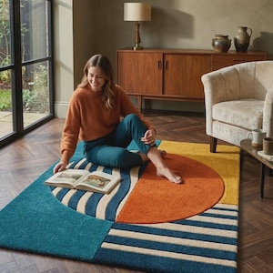 Puede incluir: Una alfombra geométrica colorida con secciones turquesa, naranja, amarilla y crema. La alfombra presenta un diseño de semicírculo y rayas. Está colocada sobre un suelo de madera en un salón.