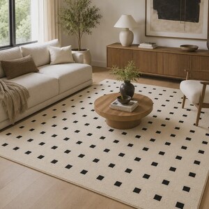 Puede incluir: Una alfombra rectangular que presenta una base de color crema con un patrón repetitivo de pequeños cuadrados negros sólidos dispuestos en una cuadrícula. La alfombra está colocada sobre un suelo de madera clara, cubriendo gran parte del suelo.