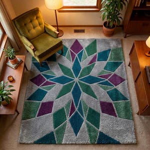 May include: A gray area rug with a geometric starburst design. The rug features a central teal star surrounded by green, purple, and teal diamond shapes. The rug is placed in a living room setting with a green armchair and wooden furniture.