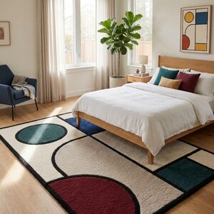 May include: A rectangular area rug featuring a cream-coloured base with bold geometric shapes in deep teal, dark red, and navy blue, outlined in black. The design includes a large red semicircle, a teal circle, and various rectangular blocks.