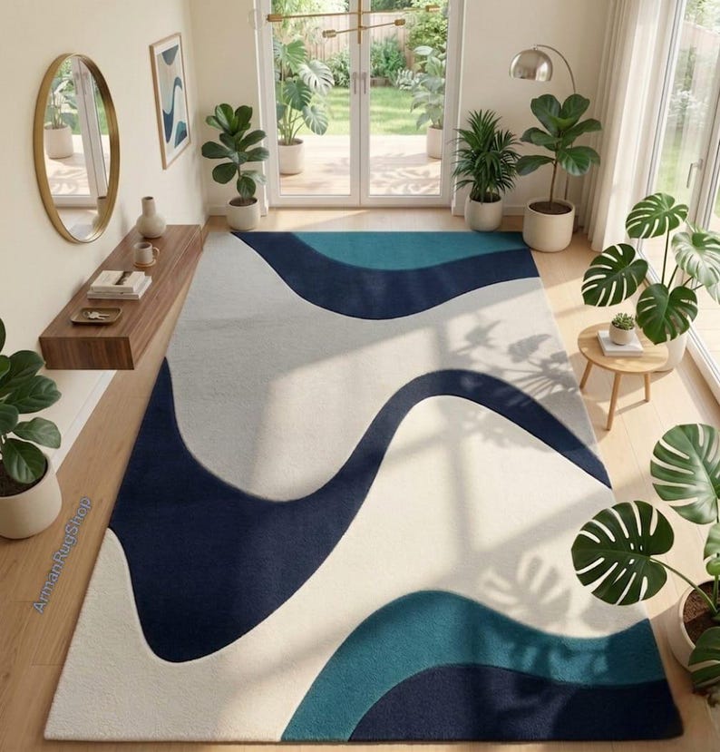 May include: A rectangular area rug featuring a large-scale abstract pattern of flowing, organic waves in shades of deep navy blue, teal, and off-white. The rug is positioned on a light wood floor in a room filled with various potted green plants.