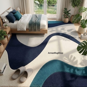 May include: A rectangular area rug featuring a wavy, abstract pattern in shades of navy blue, teal, and cream. The rug displays the text ArmanRugShop in the centre. The design consists of large, flowing organic shapes that span the entire surface.