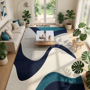 May include: A rectangular area rug featuring a large-scale abstract pattern with flowing, organic waves in shades of navy blue, teal, and cream. The rug is positioned in a living room setting and includes the text ArmanRugShop printed on the floor.