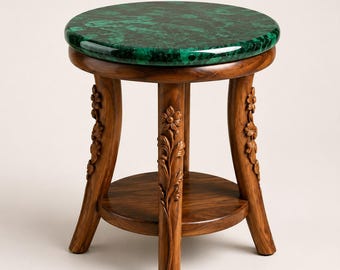 Può includere: Un tavolino rotondo con un piano in malachite verde lucida dal motivo marmorizzato. La base è realizzata in legno marrone con tre gambe, ciascuna intagliata con motivi floreali e di foglie, e include un ripiano inferiore circolare tra le gambe.