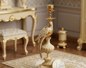 Può includere: Un portacandele a forma di pappagallo color crema e oro. Il pezzo decorativo presenta un uccello dettagliato appollaiato su un piedistallo, con una coppa per candele in cima. La base è quadrata e il design è ornato. Un oggetto decorativo elegante.