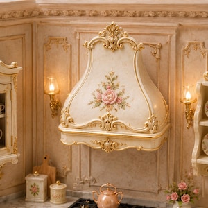May include: A miniature kitchen range hood in an off-white finish with ornate gold trim and a central floral motif featuring pink roses and green leaves. The hood is mounted on a wall with matching decorative molding and two small wall sconces.