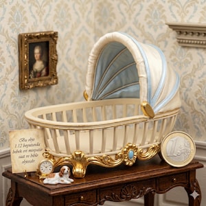 May include: A miniature cream-coloured baby cradle with a blue and cream canopy. The cradle has gold accents and is displayed on a dark wooden table. A small painting, a clock, a dog figurine, and a Euro coin are also on the table.