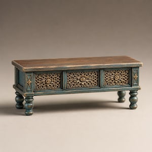 May include: A rectangular wooden bench with a dark brown top and a distressed blue frame. The front features three panels with intricate gold-colored floral filigree carvings. The piece is supported by four turned legs with a matching blue finish.