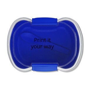 May include: A blue lunch box with a clear lid and a blue spoon inside. The text "Print it your way" is printed in white on the inside of the lunch box. The lunch box has a rectangular shape with rounded edges.