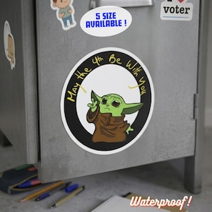 May include: A circular sticker with a green alien character in a brown robe, and the phrase "May the 4th Be With You." The sticker has a black border and is on a metal surface. Text reads "5 SIZE AVAILABLE!" and "Waterproof!"