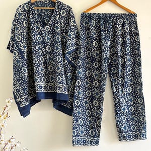 May include: A two-piece pajama set with a navy blue and white floral pattern. The set includes a short-sleeved top and matching pants, both hanging on wooden hangers. The fabric appears to be lightweight, suitable for sleepwear or loungewear.