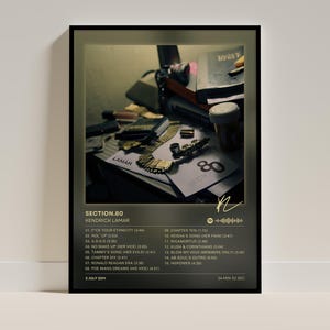May include: A rectangular wall poster featuring the Section.80 album cover by Kendrick Lamar. The design includes a dark, moody photograph of various objects, a tracklist from 01 to 15, the artist name, release date, and a Spotify code graphic.