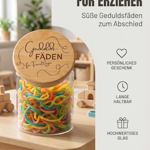 Könnte beinhalten: Ein klares Glasgefäß gefüllt mit bunten Fruchtgummi-Schnüren, verschlossen mit einem runden Bambusdeckel, der mit dem Text 'Gedulds-FÄDEN für Frau Meyer' und Schnörkeln graviert ist. Das Glas wird zusammen mit deutschem Text präsentiert.
