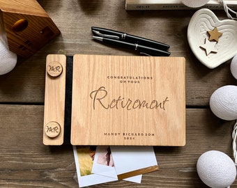 May include: A wooden retirement photo album with the words "Congratulations on Your Retirement" engraved on the cover. The album includes a photo holder and is personalized with a name and the year 2024. Two black pens are on the side.