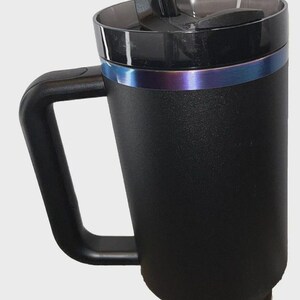 May include: Black insulated travel mug with a handle and a clear straw. The mug has a black lid with a sliding closure and a metallic blue and purple band around the middle. The mug is designed to keep beverages cold or hot.