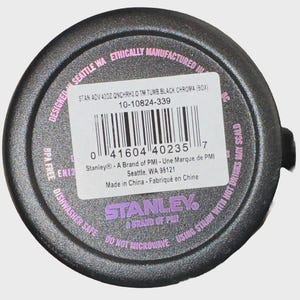 May include: Black tumbler base with a white label and a barcode. The label includes the text "STAN ADV 40OZ QNCHRH2.0 TM TUMB BLACK CHROMA (BOX)" and "Stanley - A Brand of PMI". The base also has the text "Dishwasher Safe" and "Do Not Microwave".