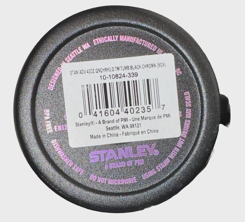 May include: Black tumbler base with a white label and a barcode. The label includes the text "STAN ADV 40OZ QNCHRH2.0 TM TUMB BLACK CHROMA (BOX)" and "Stanley - A Brand of PMI". The base also has the text "Dishwasher Safe" and "Do Not Microwave".