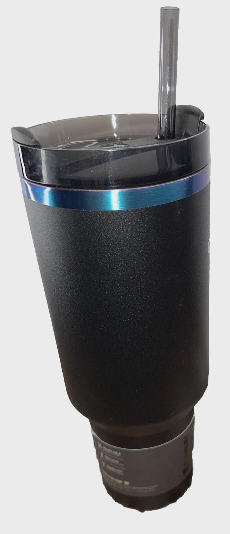 May include: Black insulated tumbler with a clear lid and a reusable straw. The tumbler has a textured surface and a blue iridescent band around the middle. The bottom portion of the tumbler is a lighter shade of black.