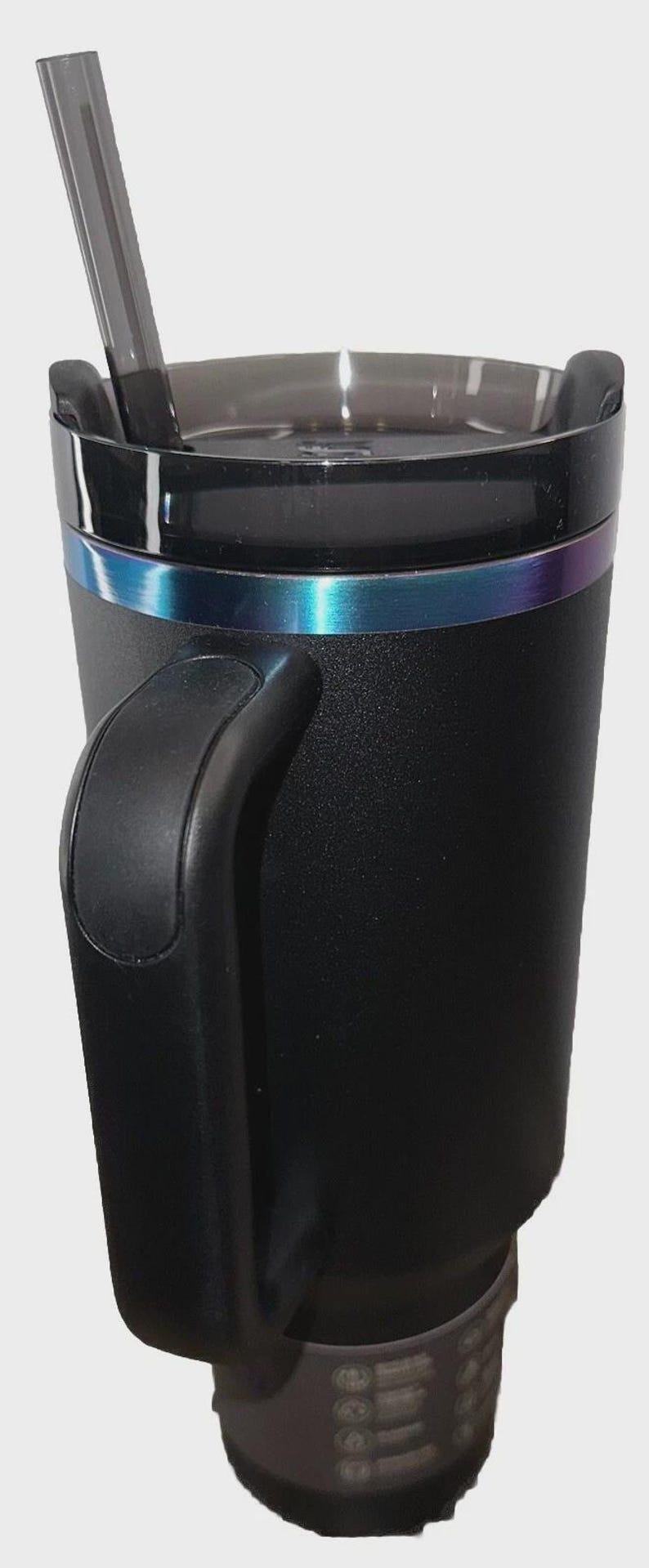 May include: Black insulated tumbler with a handle and a clear lid. The tumbler has a metallic iridescent band around the middle and a clear straw. The bottom of the tumbler has a textured design.