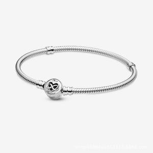 Könnte beinhalten: Ein silberfarbenes Schlangenkettenarmband mit einem runden Verschluss. Der Verschluss ist mit einem Unendlichkeitssymbol in einer Herzform graviert, wobei das Wort Love über dem Symbol und das Wort Forever darunter steht, auf einer glatten Oberfläche.