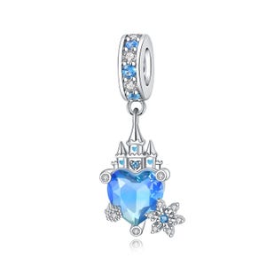 Può includere: Un charm in argento raffigurante un castello sormontato da un cristallo blu a forma di cuore. Il passante è incastonato con pietre chiare e azzurre alternate. Un piccolo charm a forma di fiocco di neve con una pietra blu centrale pende di lato.