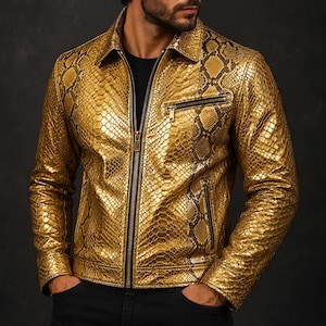 May include: A gold-colored leather jacket with a snakeskin pattern. The jacket has a zipper closure, a collared neckline, and a chest pocket with a zipper. The jacket is worn over a black shirt.