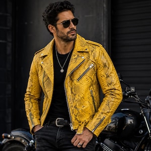 May include: A yellow snakeskin-patterned leather jacket with a classic biker style. The jacket features a notched collar, asymmetrical zipper closure, and multiple zippered pockets. The model is wearing a black t-shirt and sunglasses.