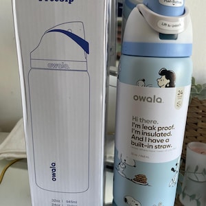 May include: A light blue Owala FreeSip insulated water bottle with a Snoopy design, featuring a push-button lid and built-in straw. The bottle is 32 oz / 945 ml and comes with a matching box.