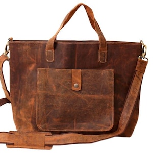 May include: A brown leather tote bag with a front pocket and a shoulder strap. The bag has two top handles and a detachable shoulder strap. The leather has a distressed look, with variations in color and texture. The bag is designed for carrying items.