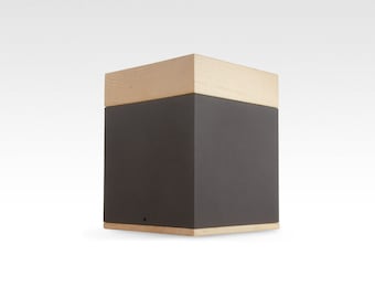 May include: A square wooden box with a dark gray lid. The box has a natural wood finish and a simple design.