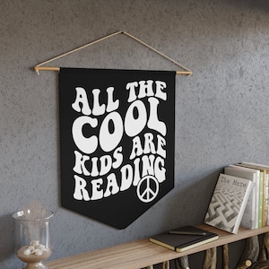 May include: Black and white wall tapestry with the text "All the cool kids are reading" in a retro font. A peace sign is at the bottom of the tapestry.