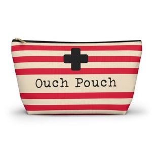 May include: Red and white striped zippered pouch with a black plus sign and the text "Ouch Pouch" printed on the front.