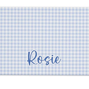May include: A blue and white gingham placemat with the name "Rosie" printed in blue cursive.