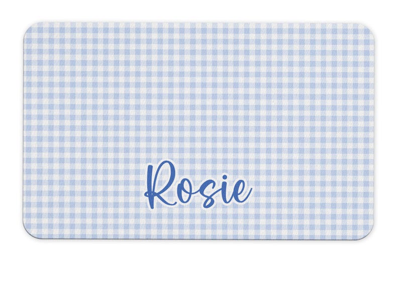 May include: A blue and white gingham placemat with the name "Rosie" printed in blue cursive.