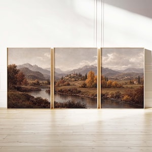 May include: A triptych wall art set featuring a continuous landscape painting of a river flowing through a valley with autumn trees, rolling hills, and distant mountains under a cloudy sky, all framed in light wood frames.