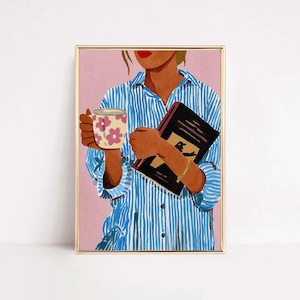 May include: A framed art print featuring a person wearing a blue and white vertical striped button-down shirt. The person holds a white mug with pink flower patterns in one hand and a black book in the other, set against a solid pink background.