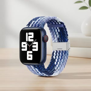 May include: A blue smartwatch with a braided band in shades of blue and white. The watch face displays the time. The band is secured with a silver clasp. The watch is a modern accessory.