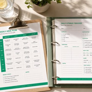 May include: A brown wooden clipboard holding a Weekly Meal Plan sheet and a green binder containing a Daily Fitness Tracker page. The meal plan features a grid for daily meals and goals. The fitness tracker includes sections for workouts, water intake, nutrition, sleep, and daily goals.