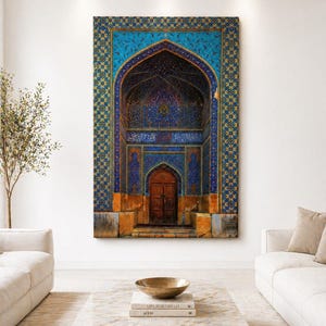May include: A large canvas print of an arched doorway with intricate blue and gold mosaic tilework. The wooden door is centered within the archway, and the artwork is displayed on a white wall above a marble coffee table.