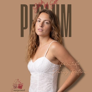 Puede incluir: Un top blanco estilo corsé de tela bordada con tirantes finos y escote corazón. La imagen incluye el texto DESIGNED BY SAGE, Stitch by Sage, PERIUM, Printable Sewing Pattern y un logotipo de 2 surprised gift attached.