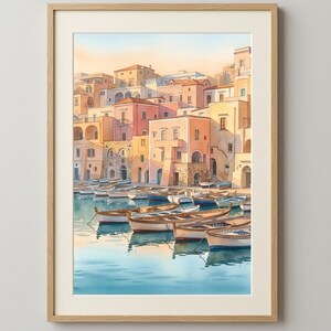 May include: A framed watercolour print depicting a coastal village with pastel-coloured buildings in shades of peach, cream, and tan, situated along a harbour filled with numerous small wooden rowboats floating on calm, light blue water.