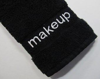 May include: Black makeup towel with white embroidery that reads "makeup".
