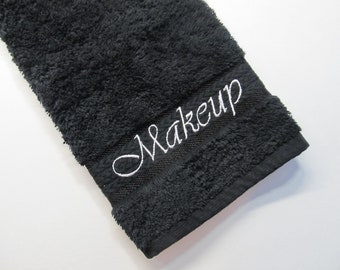 May include: Black hand towel with white embroidery that says "Makeup".